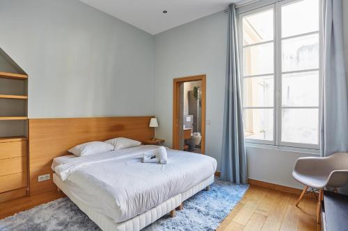 a bedroom with a bed and a large window at Apartment Ile Saint Louis by Studio prestige in Paris