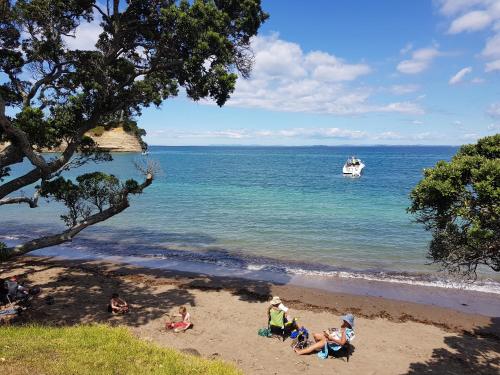 a group of people sitting on the beach at Whangaparaoa Lodge in Whangaparaoa