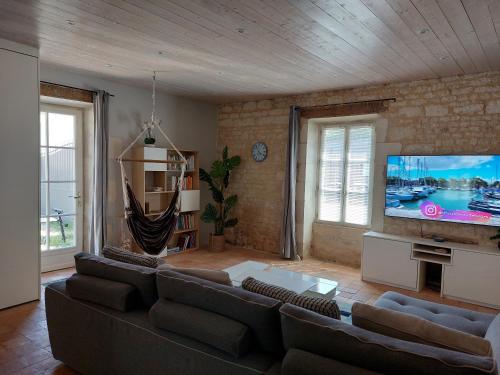 a living room with a couch and a flat screen tv at Maison pour 6 personnes avec piscine et proche de la plage in Aytré