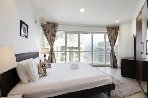 a bedroom with a large bed and a large window at SHH - Furnished 1BR Apartment in Goldcrest Executive, Jumeirah Lake Towers in Dubai