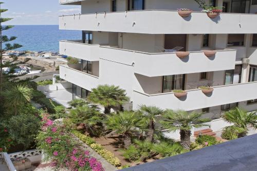 um edifício de apartamentos com palmeiras e o oceano em Casa Galli on the Seafront em Gallipoli