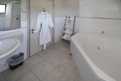 a white bathroom with a bath tub and a sink at Whangaparaoa Lodge in Whangaparaoa