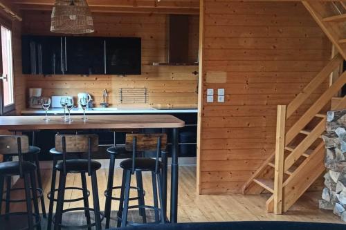 una cucina con tavolo e sedie in una cabina di Le Chalet du lac avec spa et piscine privés pour le printemps et l'été et poêle à bois réconfortant en hiver a Beaulieu