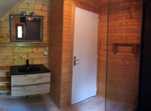 a bathroom with a white door and a sink at Le Chalet du lac avec spa et piscine privés pour le printemps et l'été et poêle à bois réconfortant en hiver in Beaulieu