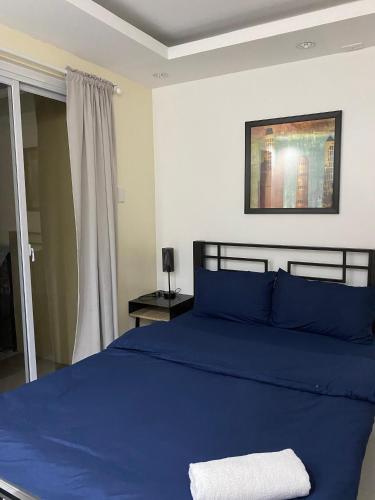 ein Schlafzimmer mit einem blauen Bett und einem Fenster in der Unterkunft Nine Balconies Island Stay in Boac