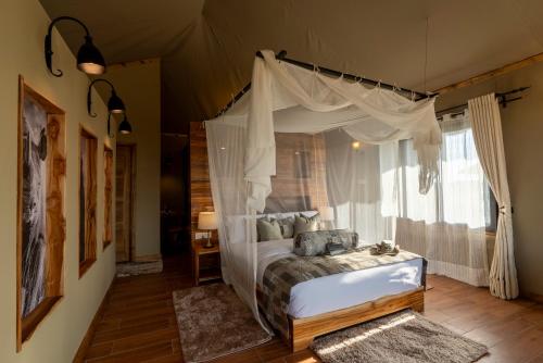 ein Schlafzimmer mit einem Himmelbett in der Unterkunft Serengeti River Camp in Robanda
