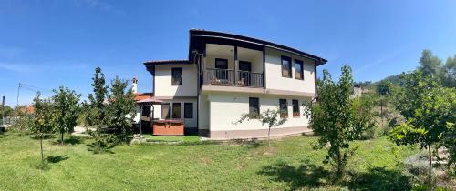 a white house with a balcony in a field at Kassandrova Guest House & Spa in Bratsigovo