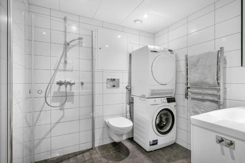 a white bathroom with a toilet and a washing machine at Rose in Sandvika