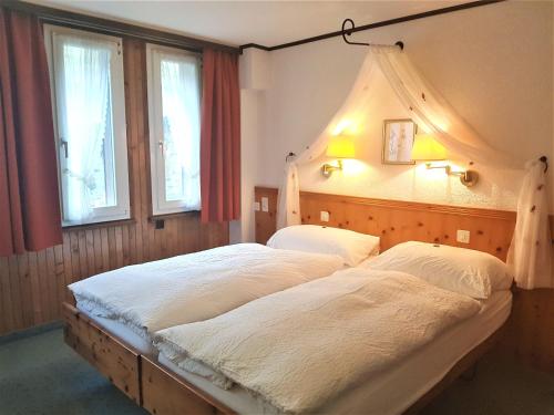 two beds in a bedroom with two windows at Self service Guesthouse Berggeist in Saas-Fee