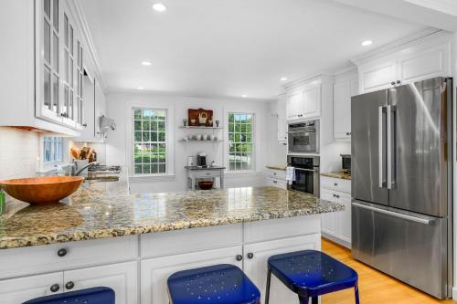 a kitchen with white cabinets and blue stools at 55 Wianno Circle Osterville - O Captain My Captain in Osterville