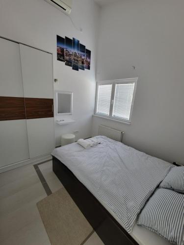 a white bedroom with a large bed and two windows at Residence Horvat in Grkavešćak