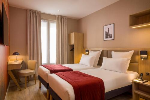 ヌイイ・シュル・セーヌにあるHotel Charlemagneのベッドとデスクが備わるホテルルームです。