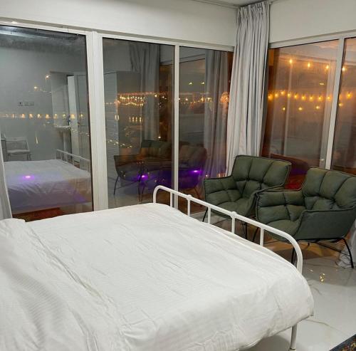 ein Schlafzimmer mit einem Bett und zwei Stühlen in einem Zimmer in der Unterkunft Al Sharq Holiday Home in Khor Fakkan