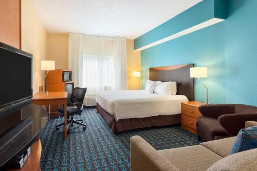 a hotel room with a bed and a flat screen tv at Fairfield Inn & Suites by Marriott Norman in Norman