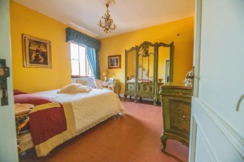 1 dormitorio con paredes amarillas, 1 cama y espejo en Suite con Bagno in villa esclusiva - Urbino, en Urbino