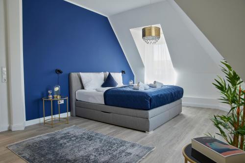 Un dormitorio con una pared de acento azul y una cama en Schlossberg Residences - XXL-Design-Apartment mit Schlossblick für bis zu 10 Personen en Schwetzingen