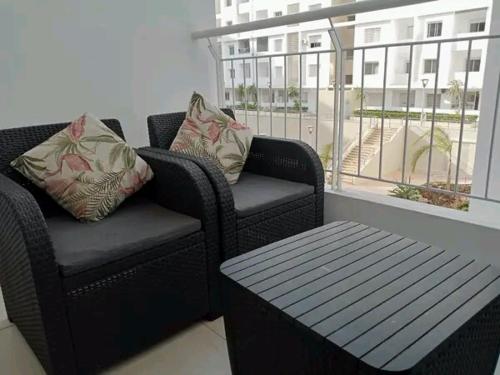 d'un balcon avec deux chaises, une table et une fenêtre. dans l'établissement Appartement meublé, à Agadir