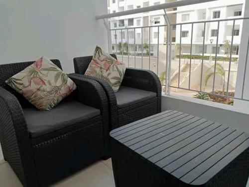 a balcony with two chairs and a table and a window at Appartement meublé in Agadir