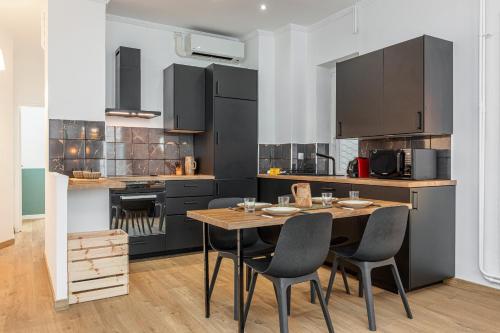 a kitchen with black cabinets and a wooden table and chairs at Confort Downtown 2 Bdr in Nice