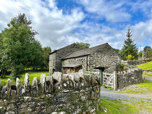 an old stone building with a fence and a gate at Mill Pool Barn Torver, Coniston in Coniston