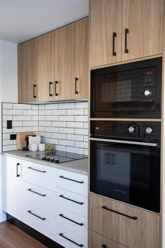 a kitchen with white cabinets and black appliances at By the Bay Batehaven - King, Queen, 2 x Singles in Batehaven