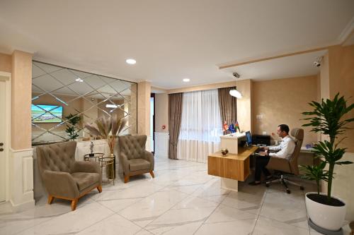 a man sitting at a desk in a lobby at Hotel Well Inn in Tbilisi City