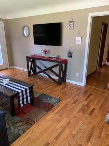 a living room with a flat screen tv and a table at Quiet home three bedroom home in peaceful neighborhood in Saginaw