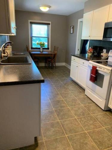 a kitchen with white cabinets and a tile floor at Quiet home three bedroom home in peaceful neighborhood in Saginaw