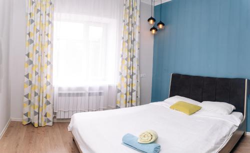 1 dormitorio con cama blanca y pared azul en Уютная и комфортная 3х комнатная в новом центре, en Uralsk