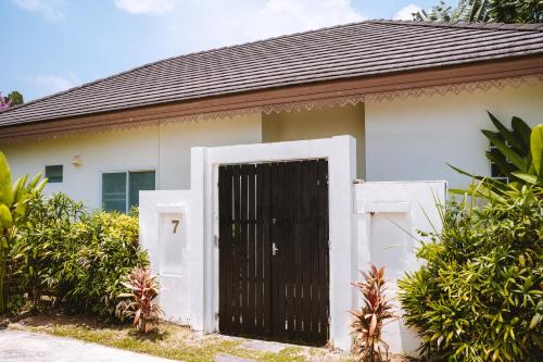 a white house with a black gate in front of it at Layantara Villas in Layan Beach