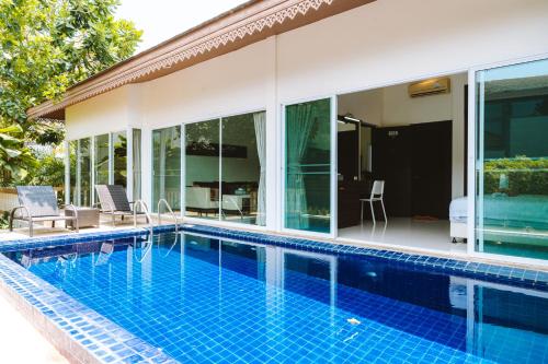 a swimming pool in front of a house at Layantara Villas in Layan Beach