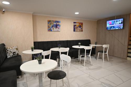 un restaurante con mesas y sillas blancas y TV en Hotel Well Inn, en Tiflis