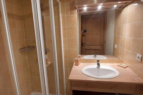 a bathroom with a sink and a shower with a mirror at Paradiski bel appartement rénové plan peisey in Peisey-Nancroix
