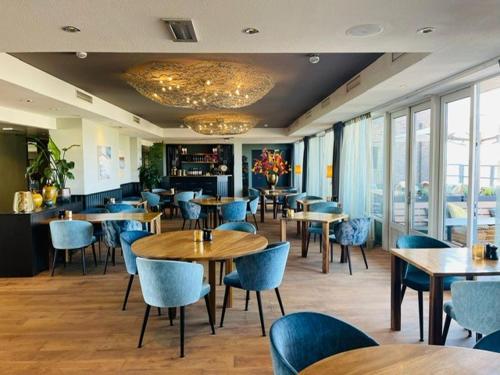 un restaurant avec des tables et des chaises en bois ainsi que des fenêtres dans l'établissement Paal 8 Hotel aan Zee, à West aan Zee