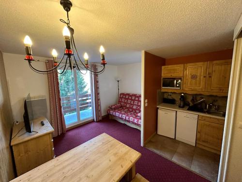a kitchen and living room with a table and a couch at Appartement les 2 alpes 1800 départ /retour skis aux pieds in Les Deux Alpes
