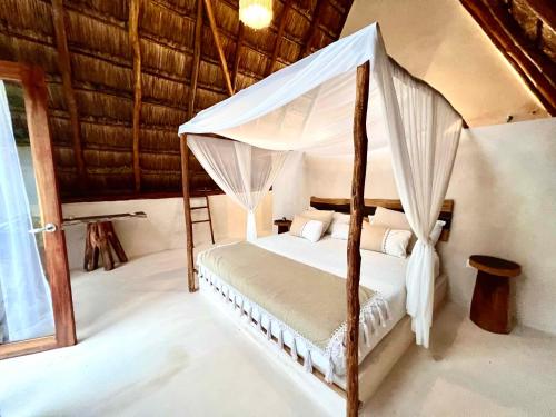 a bedroom with a bed with a canopy at Lodge Tzunum Jade in Tulum