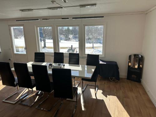a dining room with a table and black chairs at Sjöutsikt, Röd trästuga med traditionellt yttre Skandinavisk, modernt inre och alla bekvämligheter, Sol hela dagen på stora altanen, Tryggt, Vinterbonat, Fiske, Båt in Skinnskatteberg