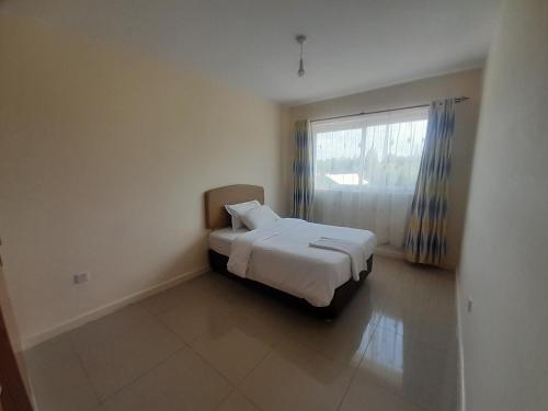 a bedroom with a white bed and a window at seville suites in Eldoret