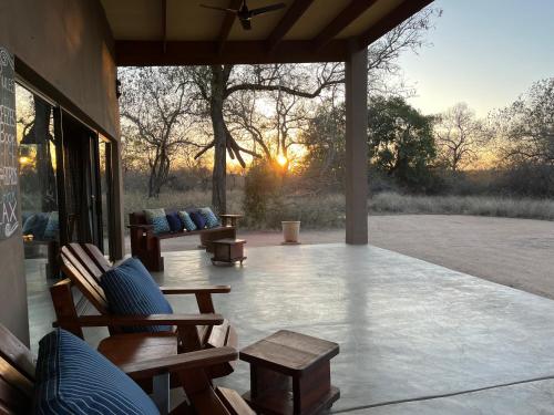 a patio with chairs and tables and the sun setting at Mananga Bush Villa in Skukuza
