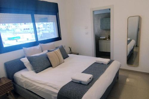 YalaRent Seasons 4 bedroom apartment with jacuzzi في إيلات: غرفة نوم بسرير كبير مع نافذة كبيرة