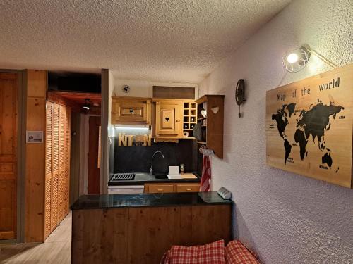 une cuisine avec des armoires en bois et une image d'une vache sur le mur dans l'établissement Appartement Montagnard Serre-Chevalier., à Saint-Chaffrey