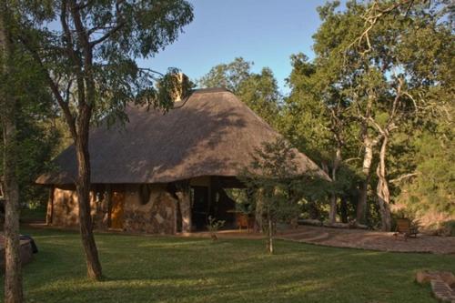a house with a thatched roof in the grass at Mbuluzi Game Reserve in Simunye