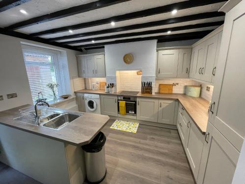 a large kitchen with white cabinets and a sink at Beautiful Mumbles/Gower cottage in Swansea