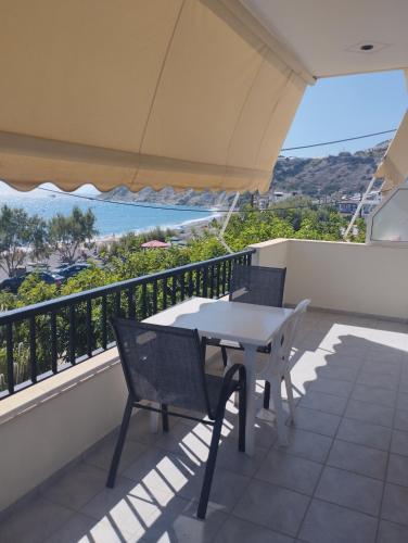 a table and chairs on a balcony with a view of the ocean at Eirini Apts On the beach in Psari Forada