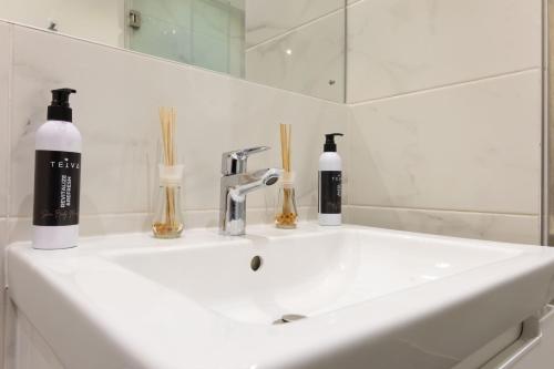 a white bathroom sink with two bottles on it at The Eden Suite in Accra
