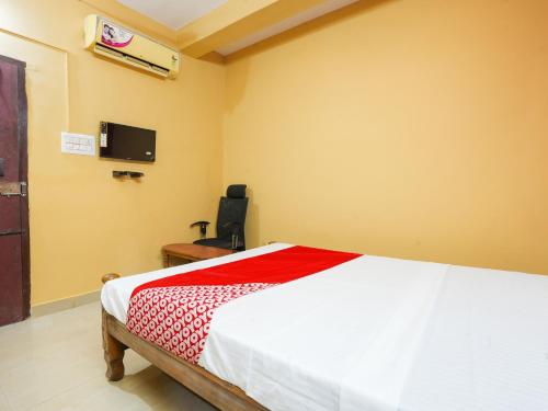 a bedroom with a bed and a tv on the wall at Hotel O Lakshmi Sri Boarding & Lodging in Bengaluru
