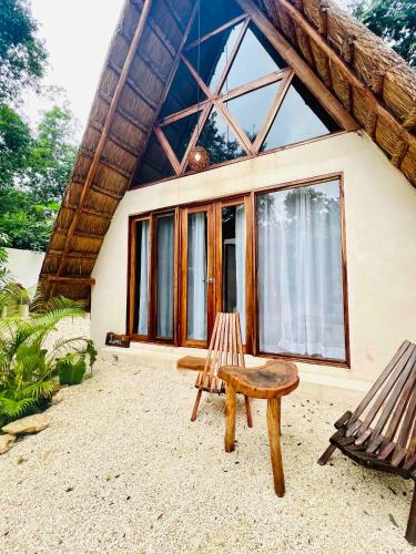 a house with a bench and a chair in front of it at Lodge Tzunum Jade in Tulum