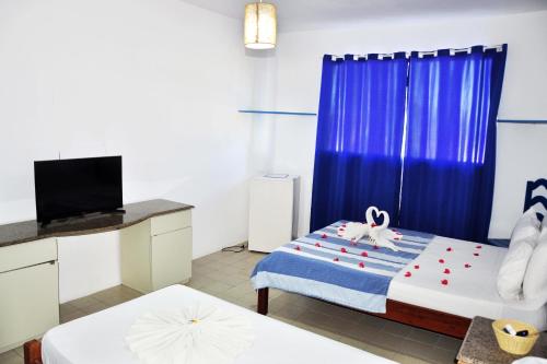 a small room with a bed and a tv at La Suite Praia Hotel in Caucaia