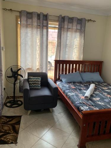 a bedroom with a bed and a chair and a window at Pearl suites in Kampala