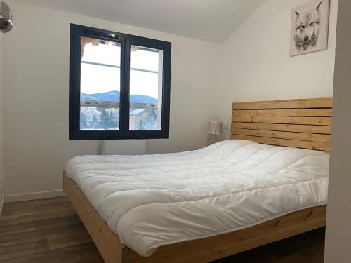 a bedroom with a bed with a wooden headboard and a window at Chalet à formiguères de type 4 terrasse in Formiguères